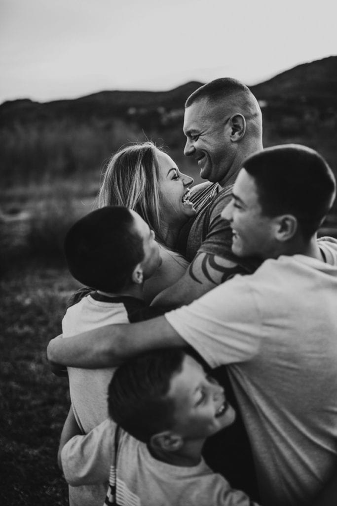 Family Photographer, mom, dad, and three sons all embrace laughing