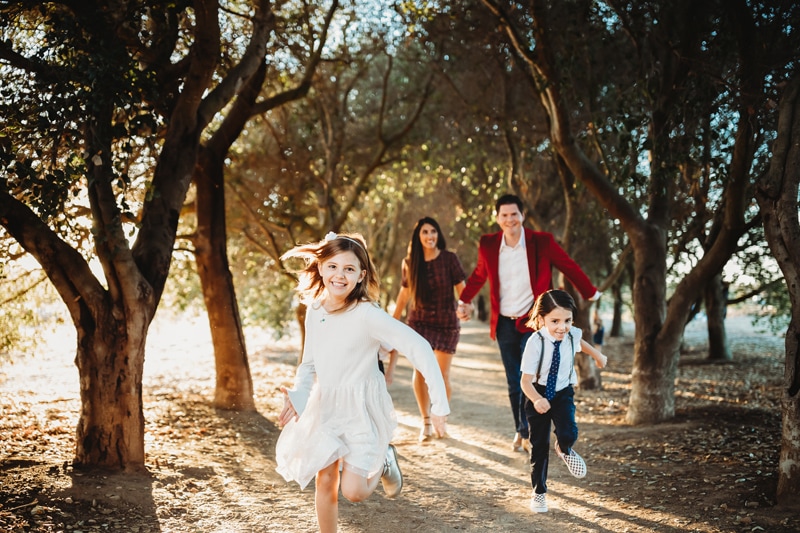 Family Photographer, A family of four runs under the trees